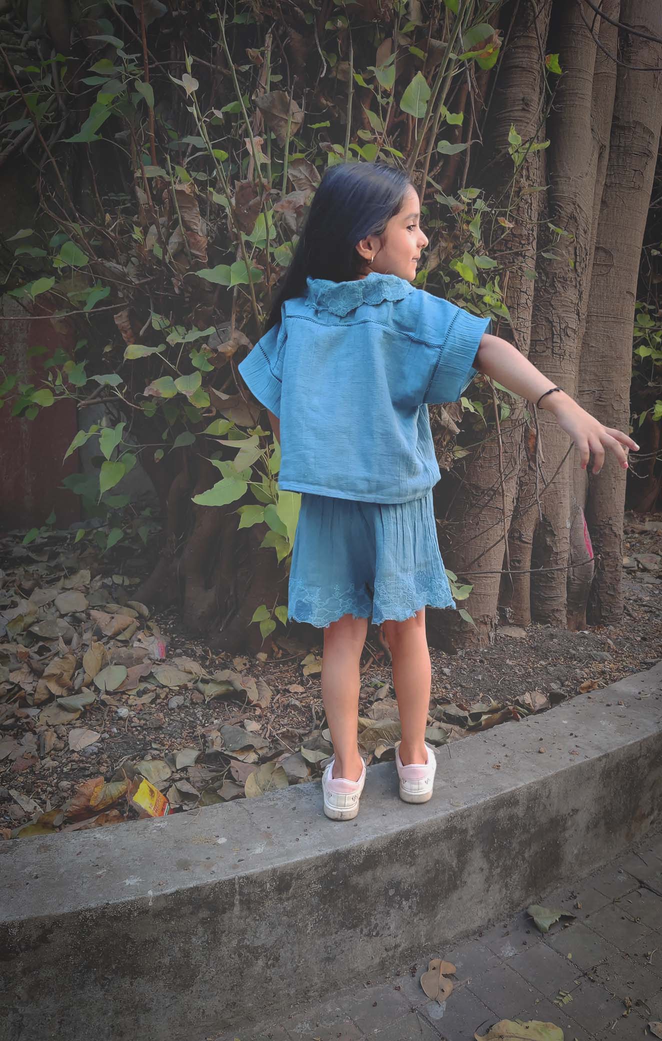 Child wearing a blue summer outfit from The Kefi House, featuring a collared top and shorts, seen from the back