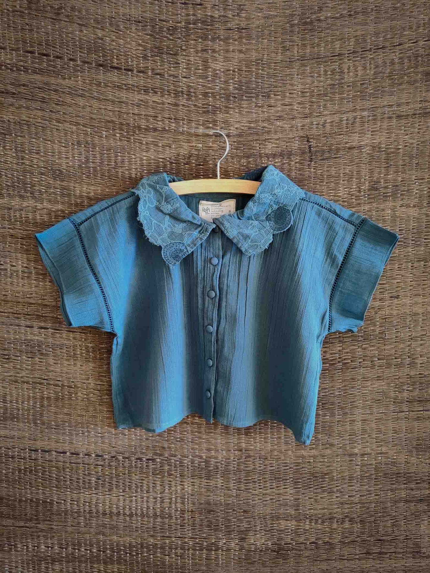 front view of The Kefi House kids' blue short-sleeve top with a charming lace-edged Peter Pan collar, designed for comfort and style.