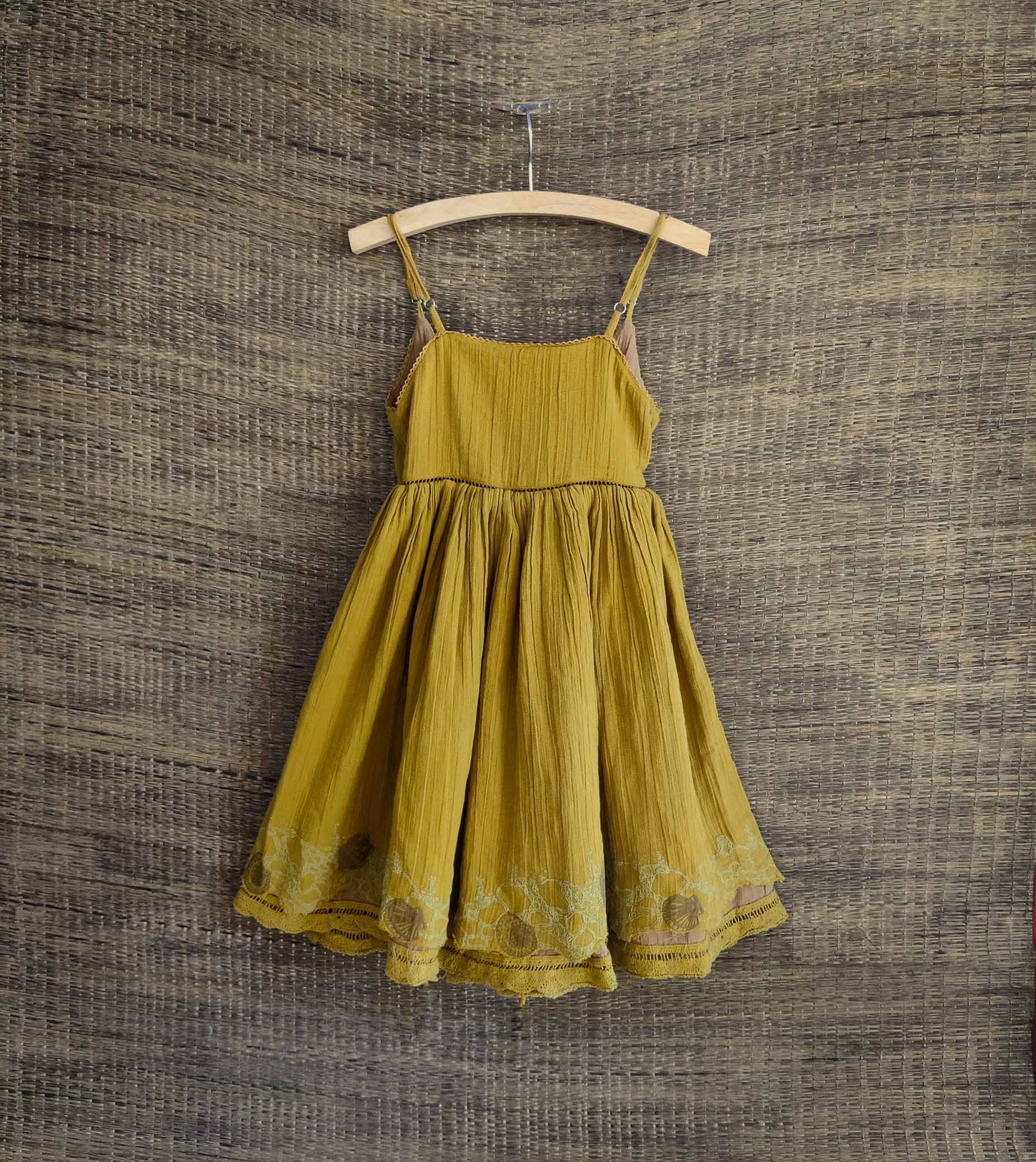 Back side of dress in yellow tone with lace hem and back tie detail