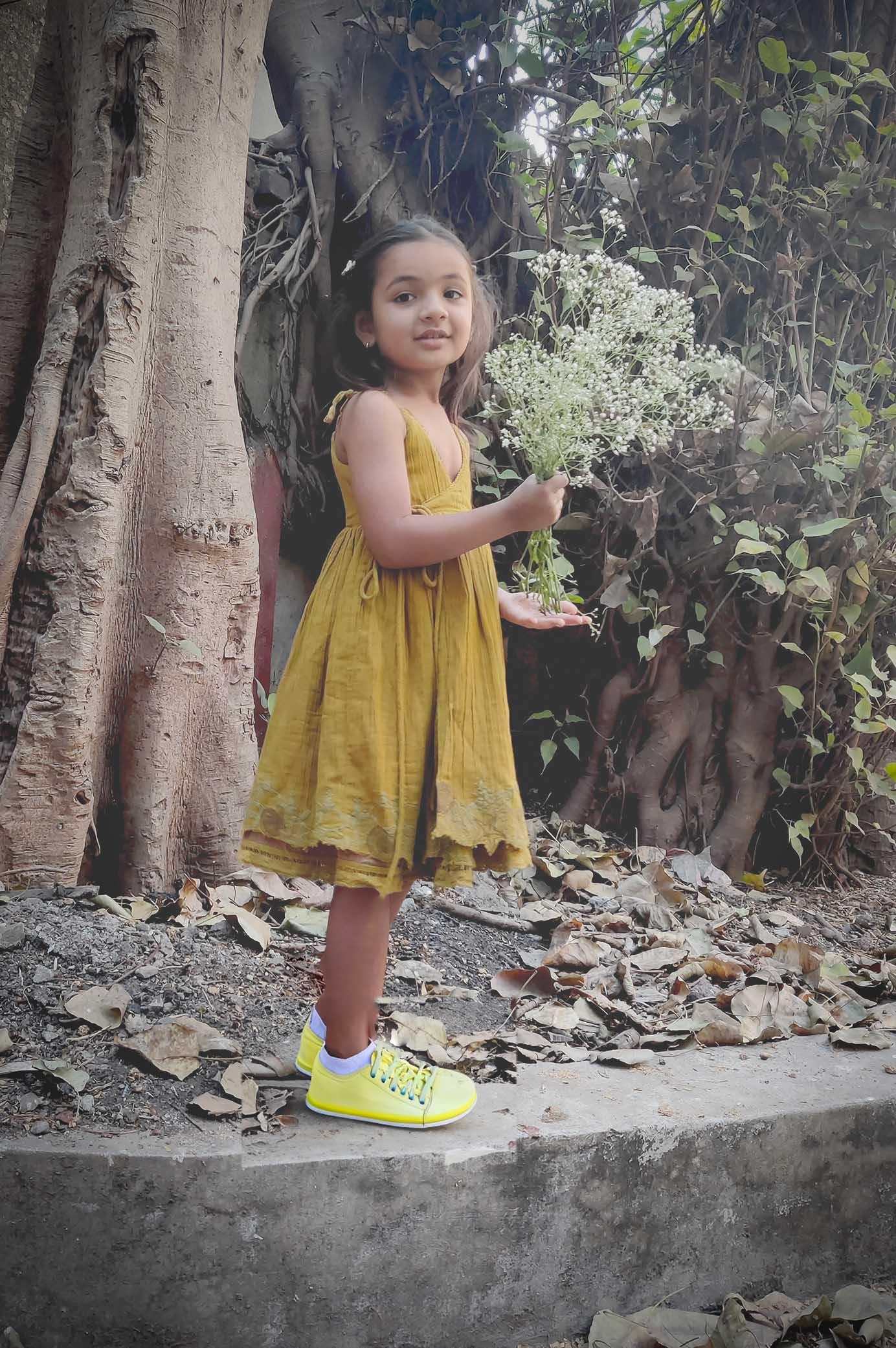 Child in a 100% cotton, breathable, reversible golden yellow dress