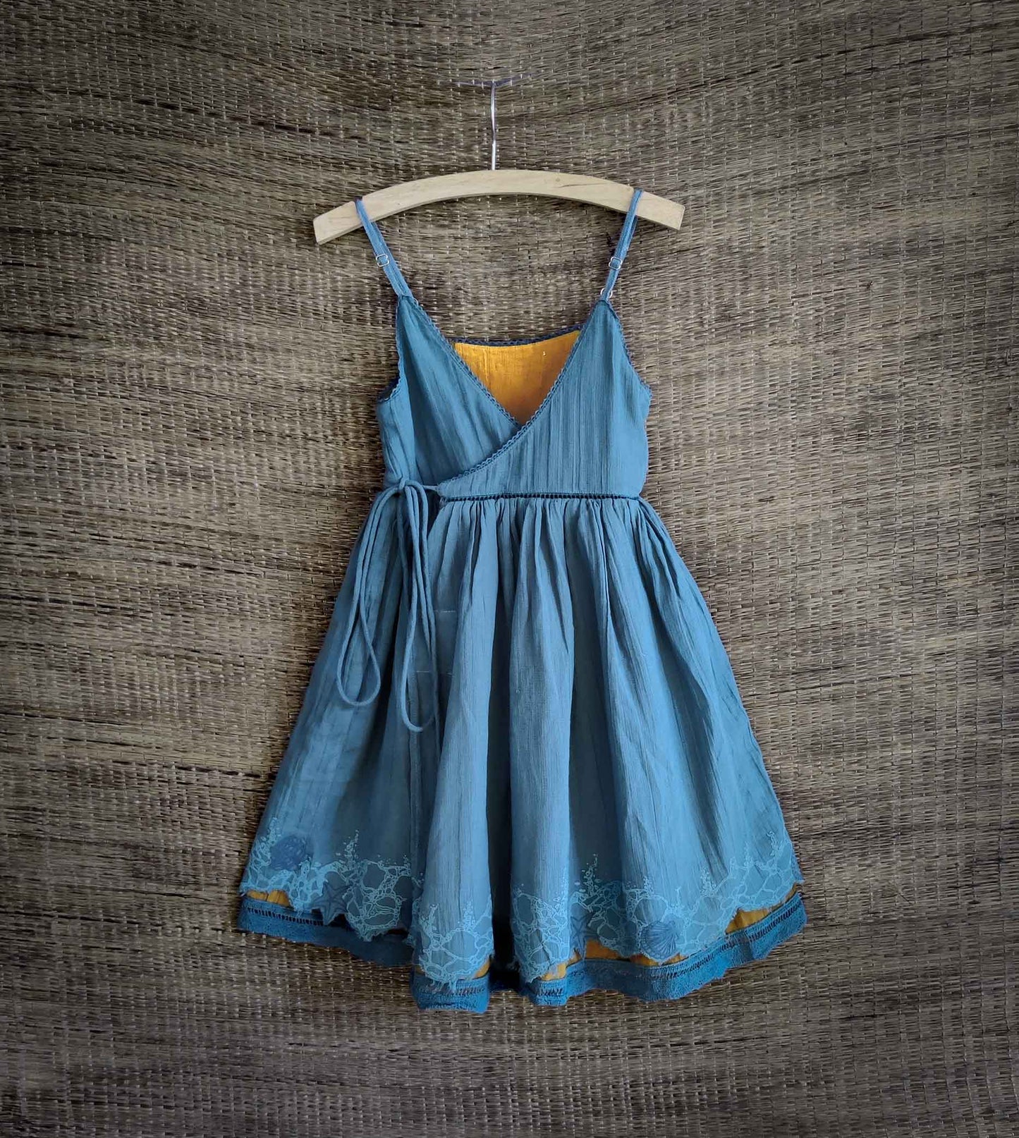 Front view of reversible wrap dress in rain blue with seafoam print hem