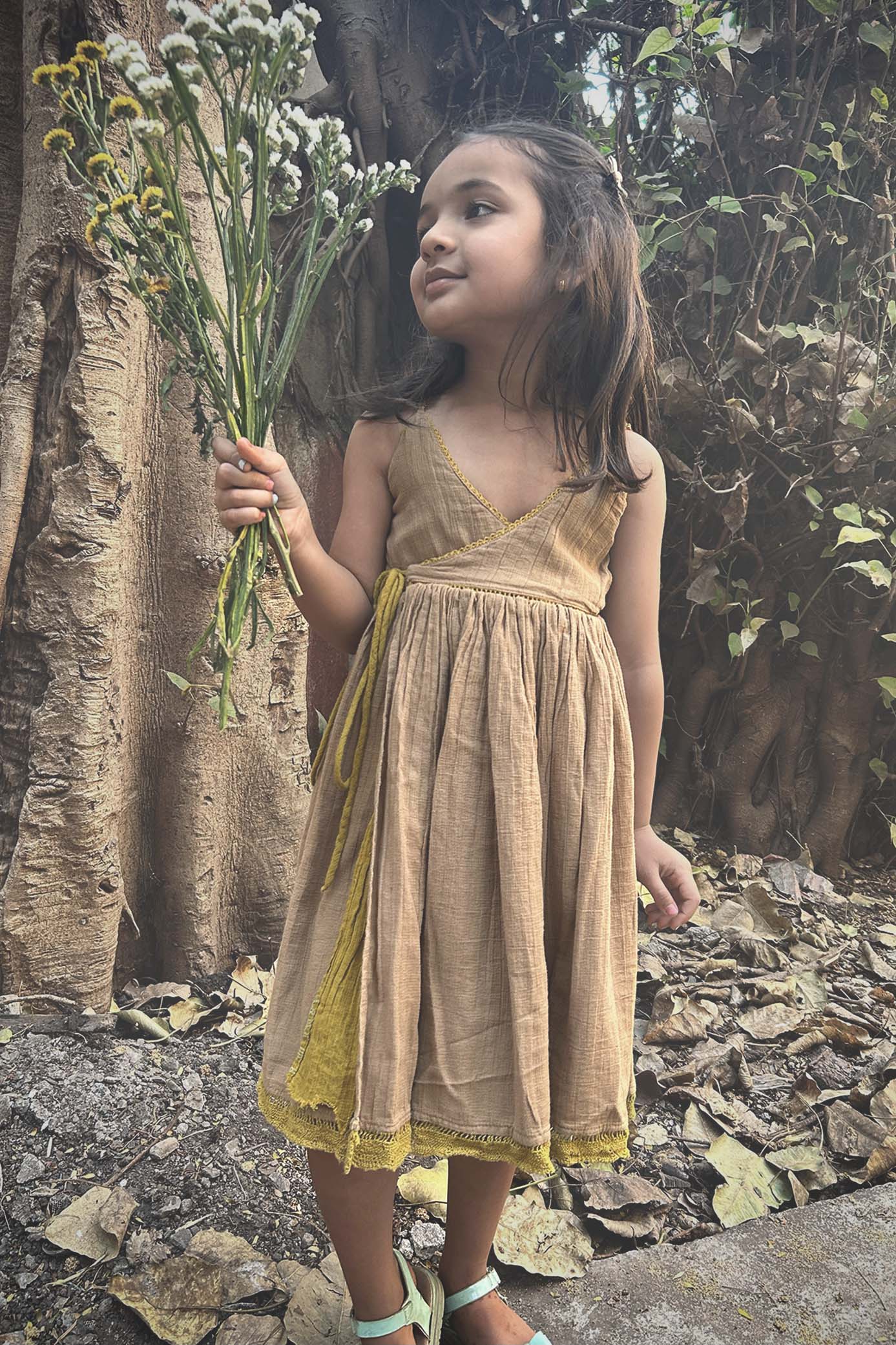 A child wearing a Golden Sun/Desert sand colour reversible dress