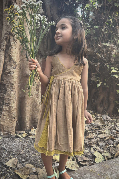 A child wearing a Golden Sun/Desert sand colour reversible dress